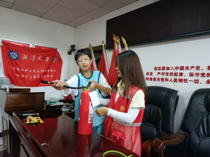 圖為志愿者向小朋友演示如何使用滅火器的場(chǎng)景
