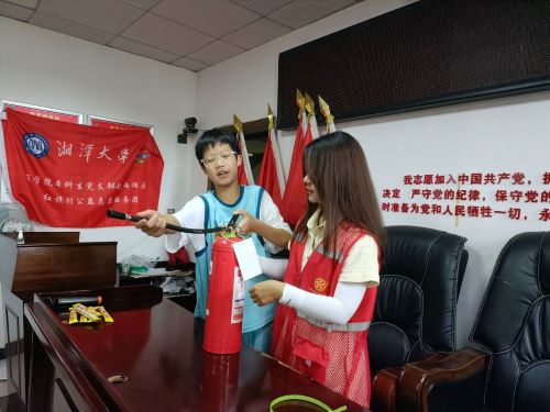 圖為志愿者帶領(lǐng)小朋友熟悉滅火器